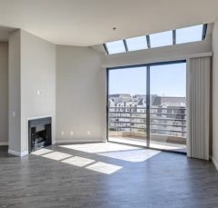 A picturesque living room with a fireplace and a breathtaking view of the city, available for rent in Hancock Park apartments.