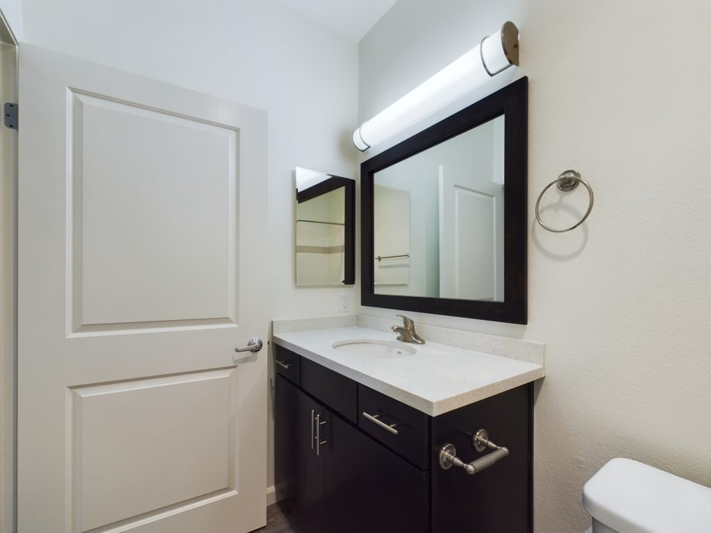 A modern apartment in Hancock Park featuring a spacious bathroom with a toilet, sink, and mirror. Perfect for those seeking apartments for rent in Hancock Park.